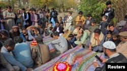 People mourn over the graves of relatives, who were killed after gunmen opened fire on passenger vehicles in the Kurram tribal district of Khyber Pakhtunkhwa province, in Shalozan