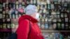 Ukraine -- CORONAVIRUS. Woman in mask walk through alcohol shop in Obolon district, ukrainian flag, Kyiv, 25Mar2020