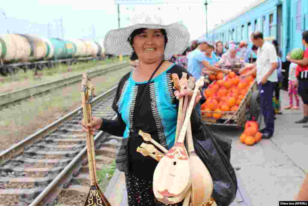 Шу темір жол станциясында домбыра сатып тұрған әйел.